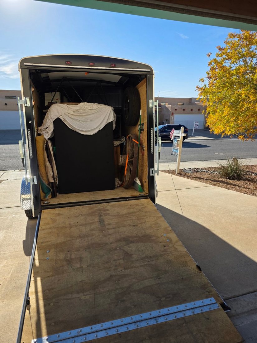 Enclosed trailer packed with staging furniture, ramp down at a Las Cruces home