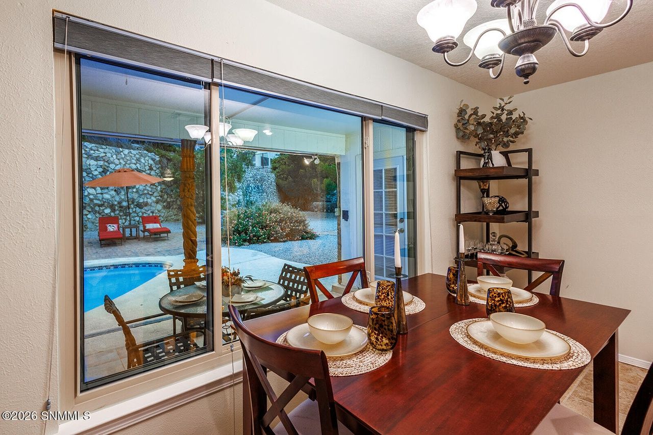 Staged dining table set for dinner beside a pool-view window, Salinas Drive Las Cruces