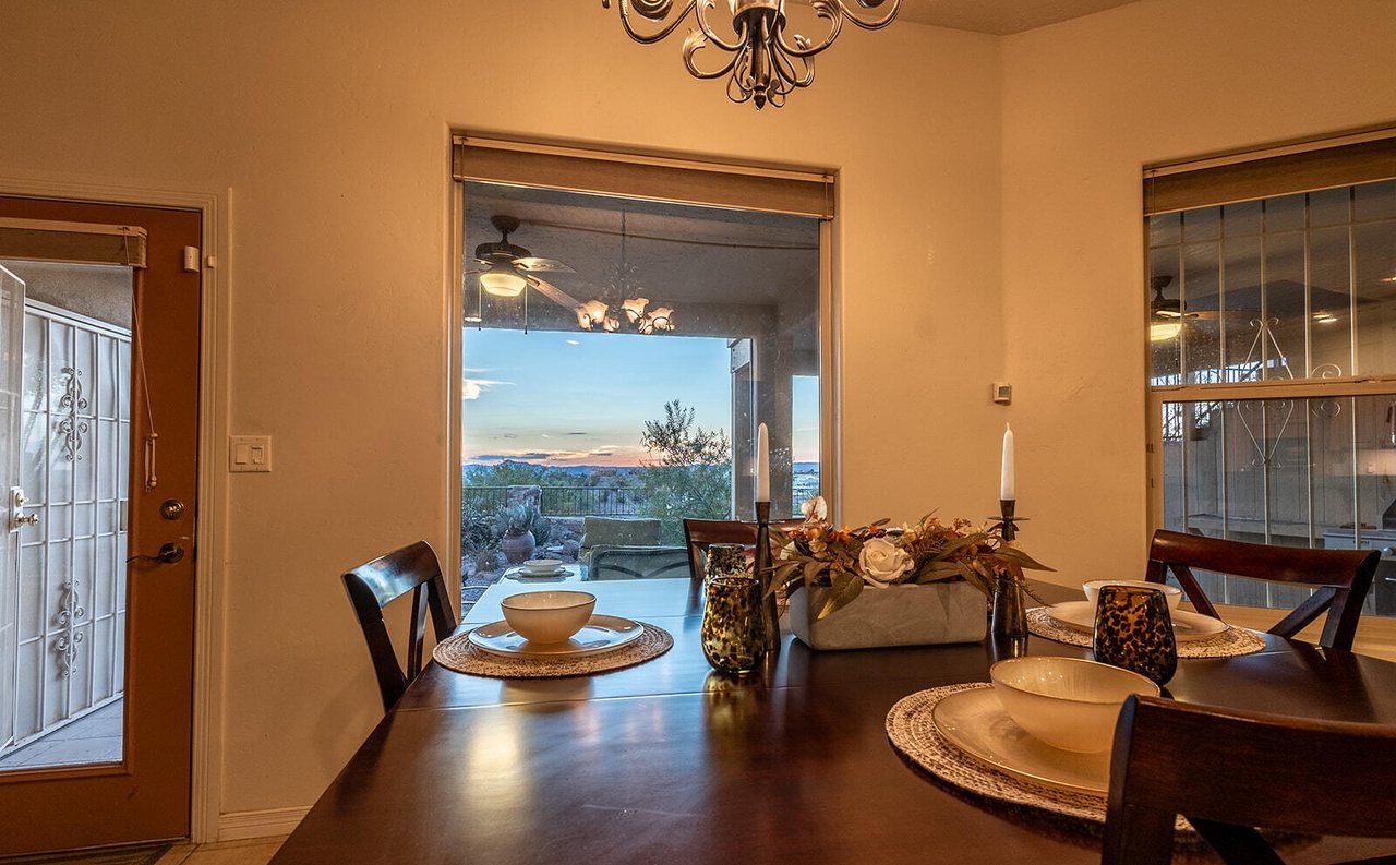 Staged dining table set for dinner with a sunset view through the patio door, Sedona Hills Las Cruces