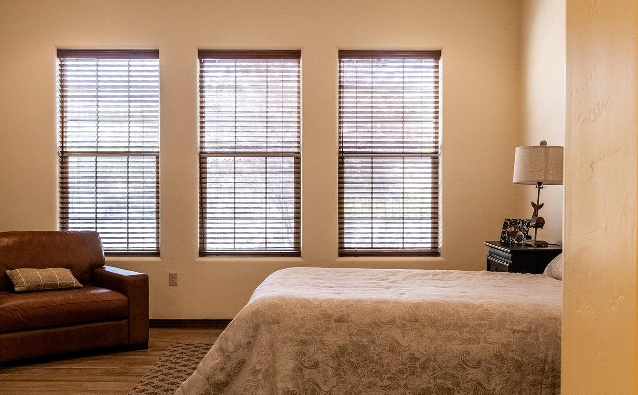 Staged guest bedroom with real bed, leather loveseat and lamp, Sedona Boulders Las Cruces NM