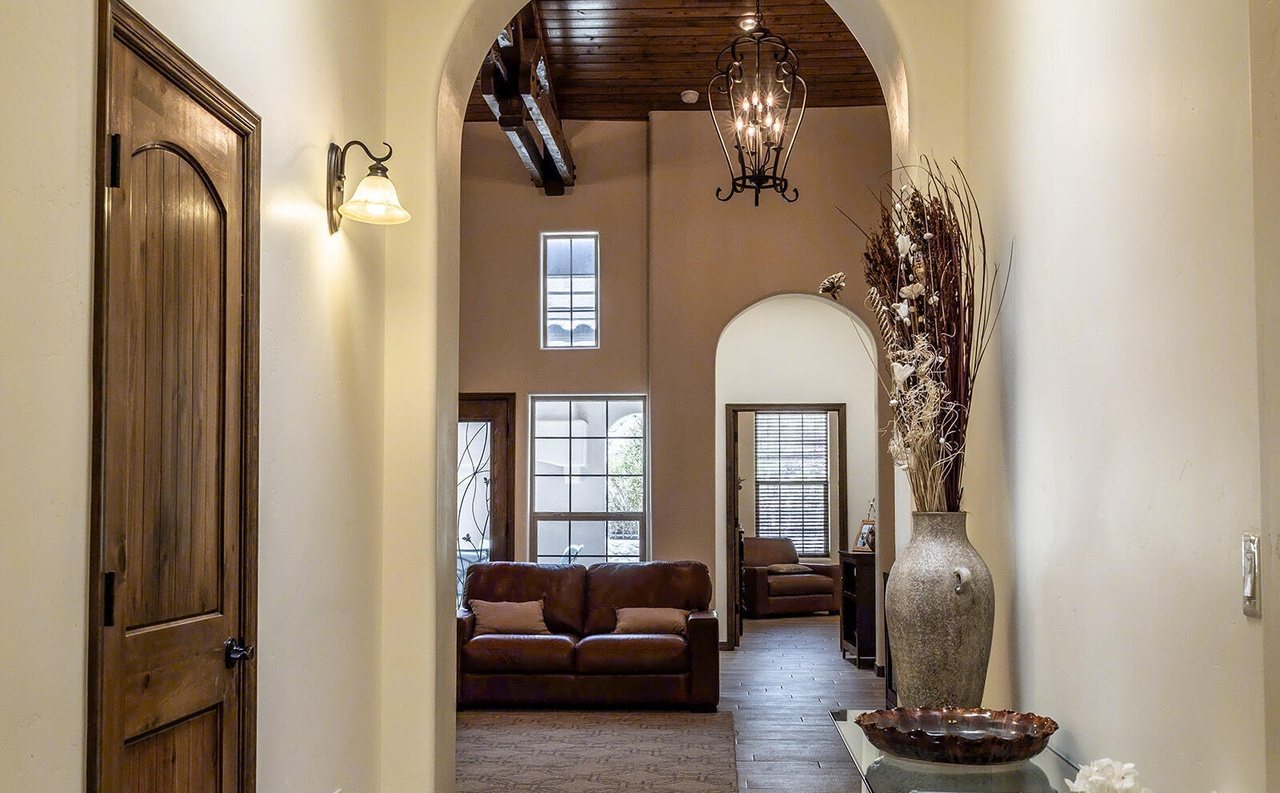 Staged hallway opening to a living room with leather sofas, Sedona Boulders Las Cruces
