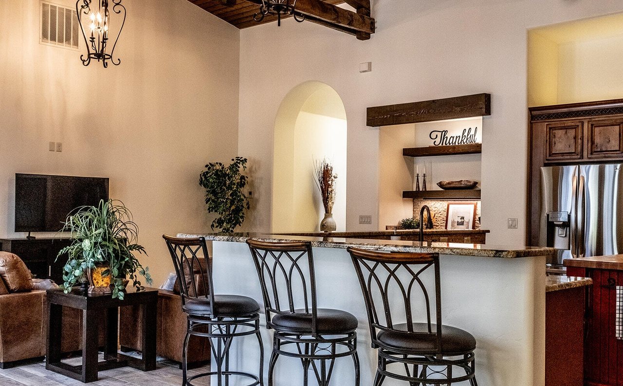 Staged kitchen island with iron bar stools and living room, Sedona Boulders Las Cruces