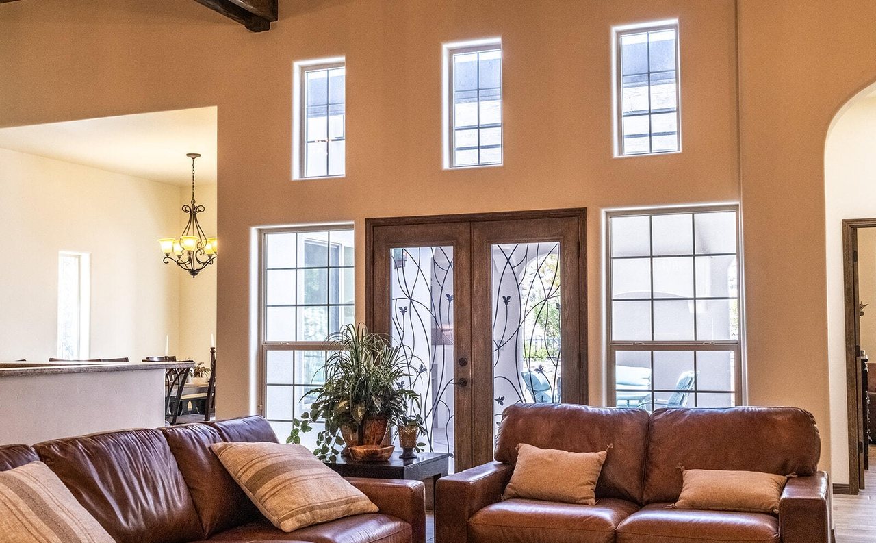 Staged living room under tall windows with leather seating, Sedona Boulders Las Cruces