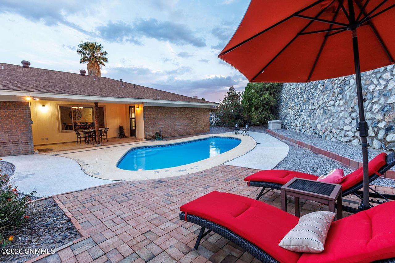 Staged backyard pool patio with red loungers and umbrella, outdoor living staging Las Cruces