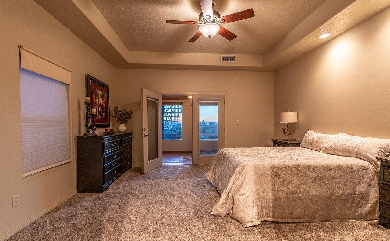 Staged primary bedroom with real bed, dresser and nightstand lamp, Sedona Hills Las Cruces